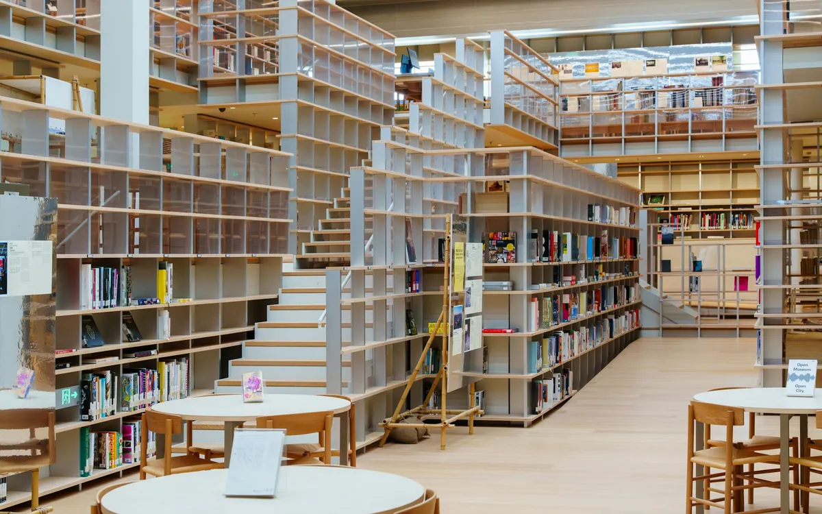 Çok katlı raf sistemleri ve çalışma masaları olan modern bir kütüphane