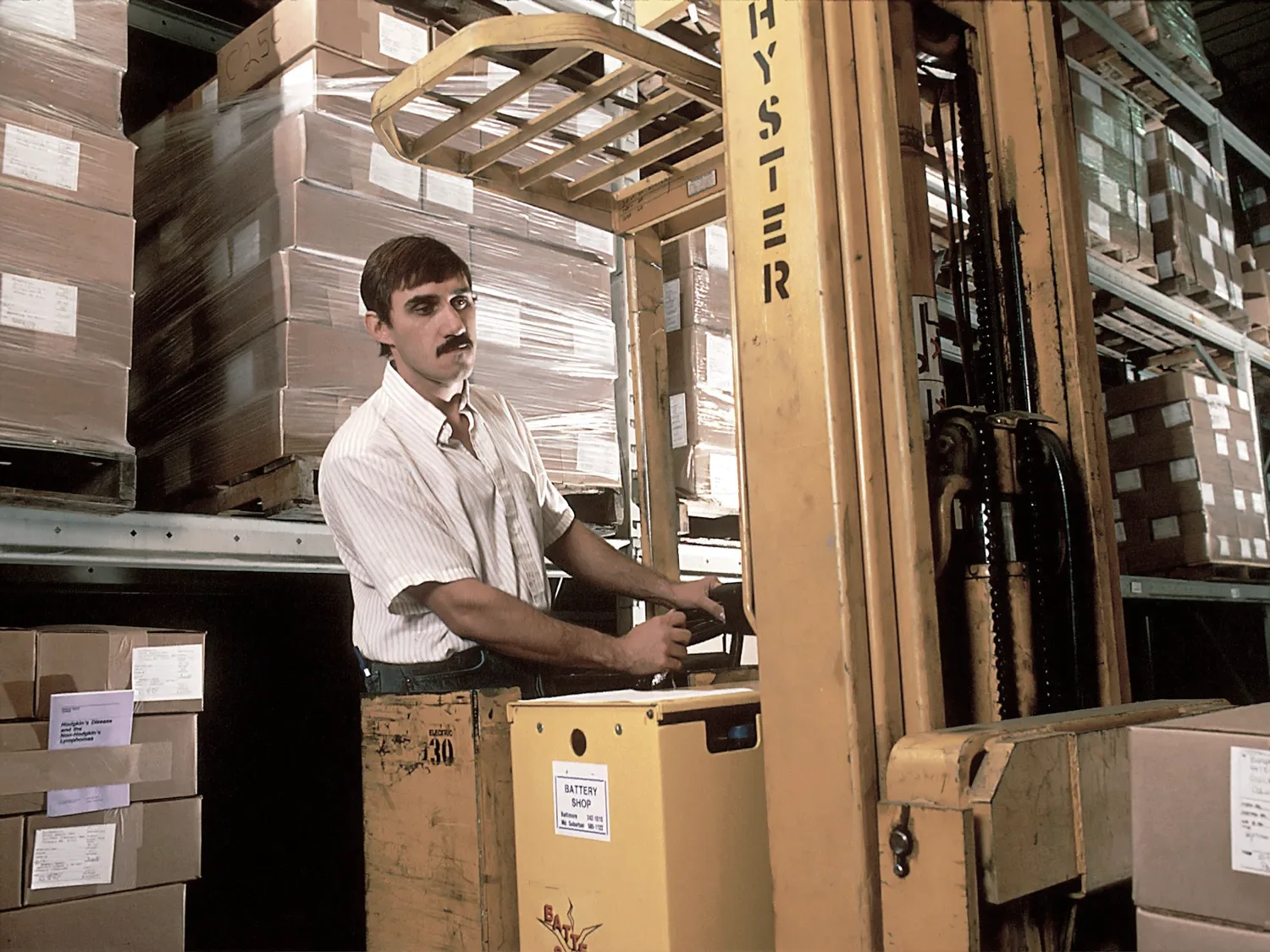 Bir depoda forklift operatörü koli yüklerken.